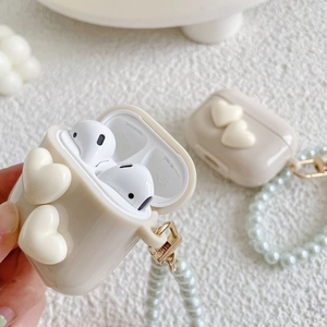 Macro shot of cream heart-shaped AirPods Pro case with elegant pearl bead hand strap