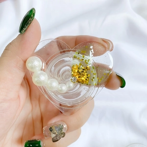 Macro view of heart-shaped phone grip with white pearls and gold glitter inside