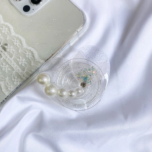 Detail of heart-shaped resin phone grip with pearls and teal floral glitter inlay