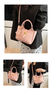 Detail of pink lychee leather bucket bag featuring gold buckle and cute puppy pendant