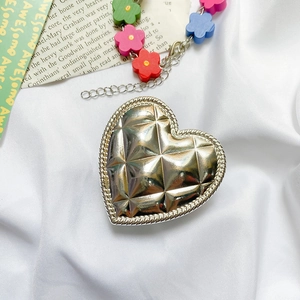 Close-up of heart-shaped metal phone holder with quilted texture and gold chain link
