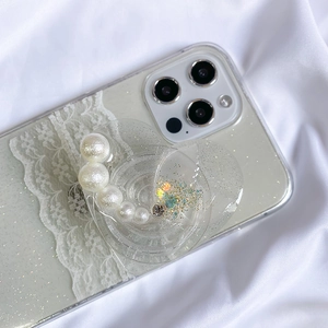 Detail view of heart-shaped glitter phone grip with white pearls on a lace phone case