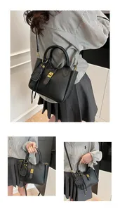 Detailed view of black lychee grain leather bucket bag with gold lock and dog charm