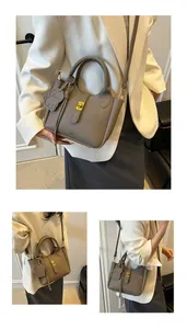 Detail of grey lychee leather bucket bag with metal lock and cute dog charm attachment