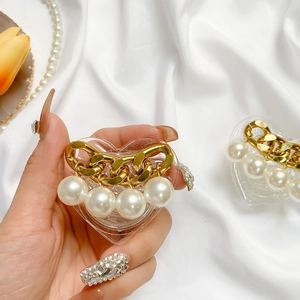 Detail view of heart-shaped acrylic phone grip with gold chain and white pearls decoration