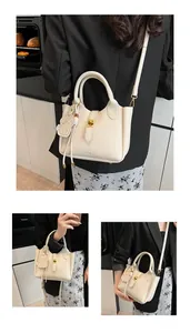 Detail view of beige lychee leather bucket bag with cute dog charm and PAN FOR logo