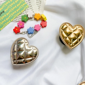 Macro shot of heart-shaped metal phone grips with quilted pattern in gold and silver