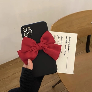 Detail der matten iPhone Hülle in Schwarz mit großer roter Satinschleife und Kamera-Ausschnitt