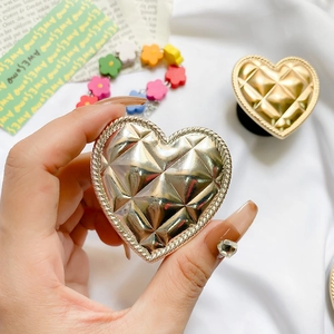 Detail of a heart-shaped gold metallic phone grip with quilted texture and rope-braid edge