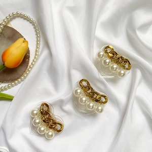 Detailed shot of heart-shaped pearl phone grip with gold chain on white satin