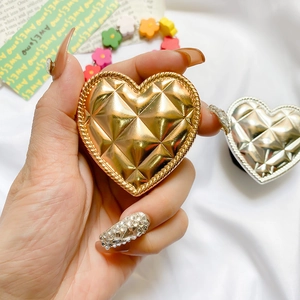 Close-up of heart-shaped metallic phone grip with quilted pattern and electroplated finish