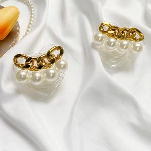 Macro detail of heart-shaped glitter phone grip with gold chains and pearls on silk