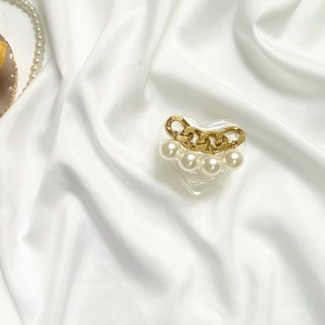 Macro shot of heart-shaped hair claw clip with gold chain and white pearl details