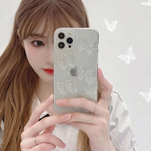 Detail of transparent iPhone case with 3D glitter bow ties shown held by a hand