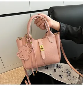Detail of pink lychee leather bucket bag with gold twist lock and dog charm