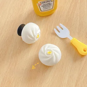 Macro shot of two custard bun phone grips on wood surface with yellow kitchen props