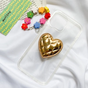 Detail of a transparent phone case with a gold quilted heart foldable socket stand