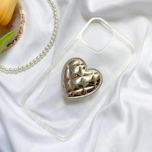 Close-up of golden heart phone socket with quilted texture and chain detail on clear case