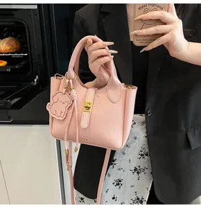 Detailed shot of pink lychee leather bucket bag with gold clasp and dog charm
