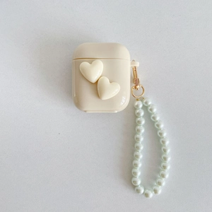 Detail view of cream white AirPods case with double 3D hearts and pearl wrist strap