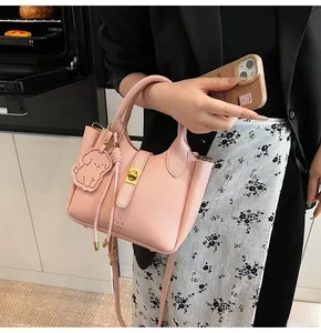 Pink lychee grain leather bucket bag with gold lock and puppy charm in a casual scene
