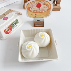 Close-up of two cute steamed bun squeeze toys in a plastic storage box on a desk