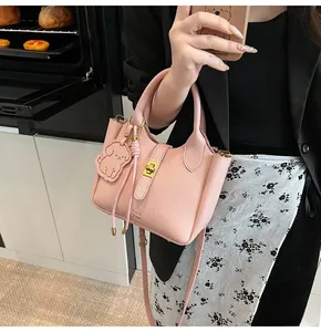 Detailed macro shot of pink lychee pattern leather bucket bag with gold clasp and dog charm