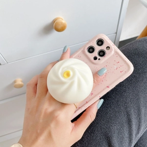 Close-up of a 3D dumpling phone socket on a pink speckled case held by a person