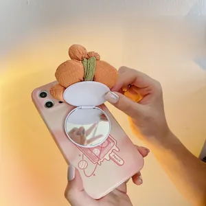 Detail of peach themed phone case featuring a foldable fabric mirror for makeup touch-ups