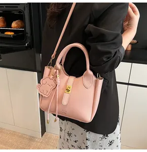 Detailed close-up of pink litchi grain leather bucket bag with dog charm and metal lock