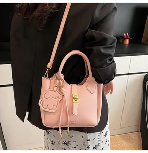 Detail of pink lychee leather bucket bag with gold hardware and dog charm
