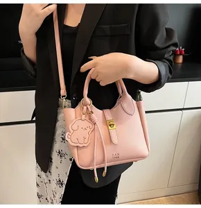 Detailed view of pink lychee leather handbag featuring a gold twist lock and dog charm