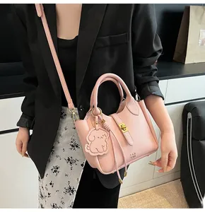 Pink lychee grain leather bucket bag with gold hardware and white puppy charm detail