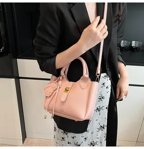 Detail of pink lychee grain leather handbag with gold twist lock and dog bag charm