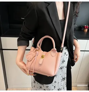 Pink lychee grain leather bucket bag featuring a gold twist lock and a cute puppy charm