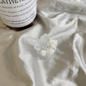 Detail of expandable phone grip with iridescent butterfly, white roses and pearls