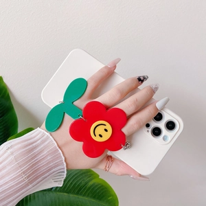 Detail of white iPhone case with red floral bracelet and yellow smiley face charm