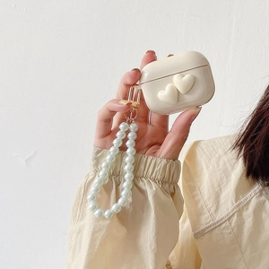 Creamy white AirPods case featuring 3D hearts and elegant faux pearl wrist strap charm