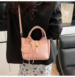 Detail of pink lychee grain leather bucket bag featuring a cute puppy charm and gold hardware