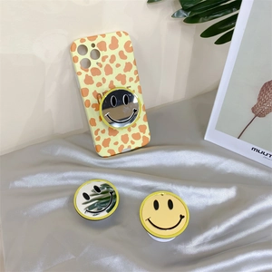 Detail of yellow leopard print phone case and reflective smiley face pop socket