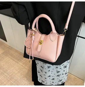 Pink lychee grain leather bucket bag with gold lock and puppy charm on model