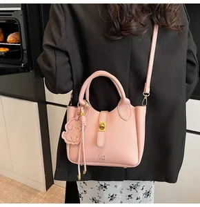 Detail of pink lychee leather bucket bag with gold twist lock and dog charm