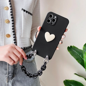 Detail of matte black iPhone case with 3D white heart and chunky chain strap held by a person