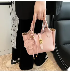 Detail of pink lychee leather bucket bag with golden lock and dog charm