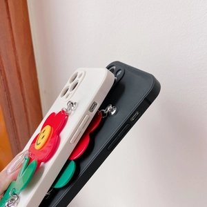 Detail view of iPhone silicone case with red sunflower charm and precise button cutouts