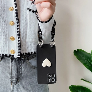 Detail of black phone case featuring white heart decor and chunky acrylic chain strap