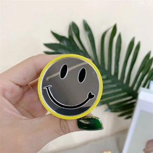 Detail of expandable round yellow phone grip with built-in mirror and black smiley face
