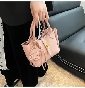 Detail view of pink lychee grain leather bucket bag with puppy charm and gold lock