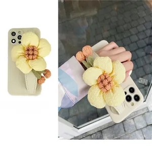 Detail of cream iPhone case with a large fabric sunflower wristband and plush orange balls