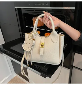 Detailed view of beige lychee texture leather bucket bag with gold lock and dog charm